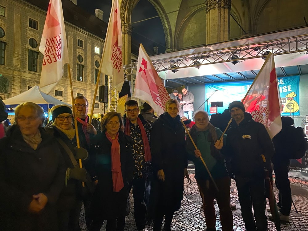 Teilnehmerinnen und Teilnehmer der KAB mit Fahnen vor der Bühne am Odeonsplatz.